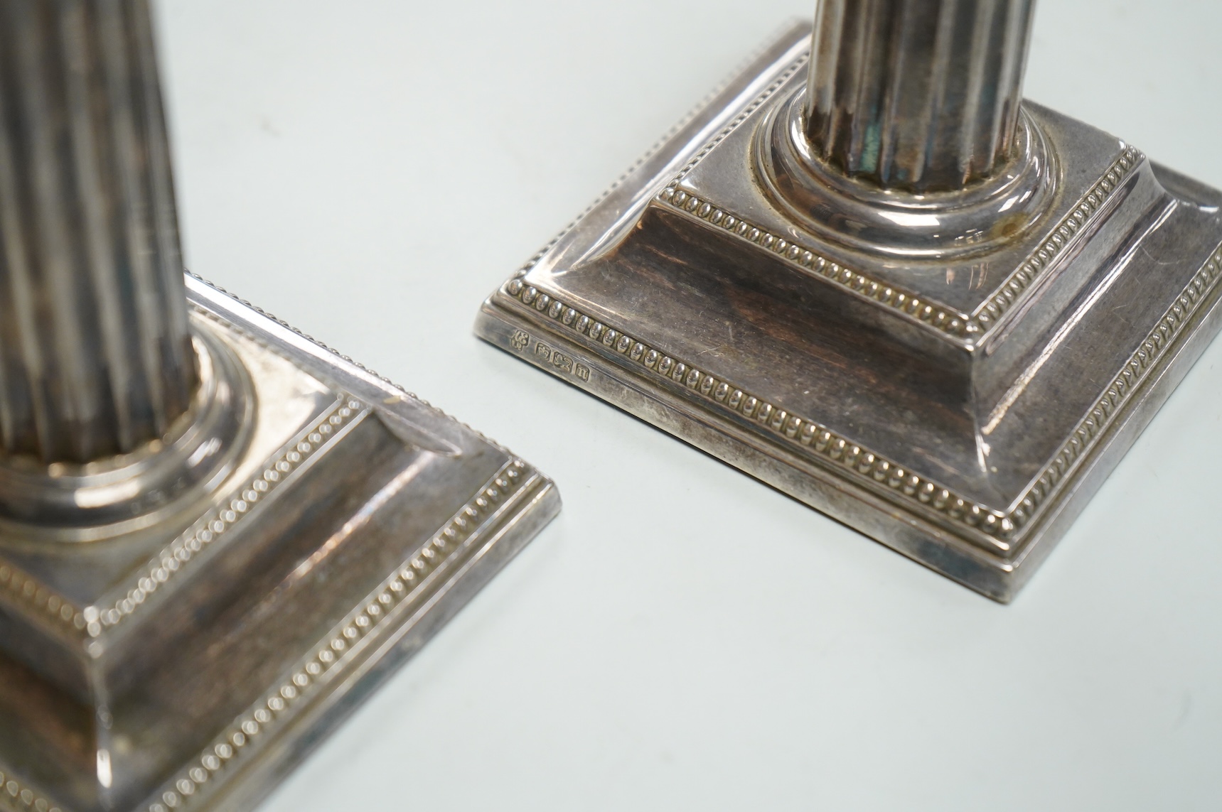 A pair of Edwardian silver mounted fluted column candlesticks, by Hawksworth, Eyre & Co, Sheffield, 1905/6, height 12cm, weighted.